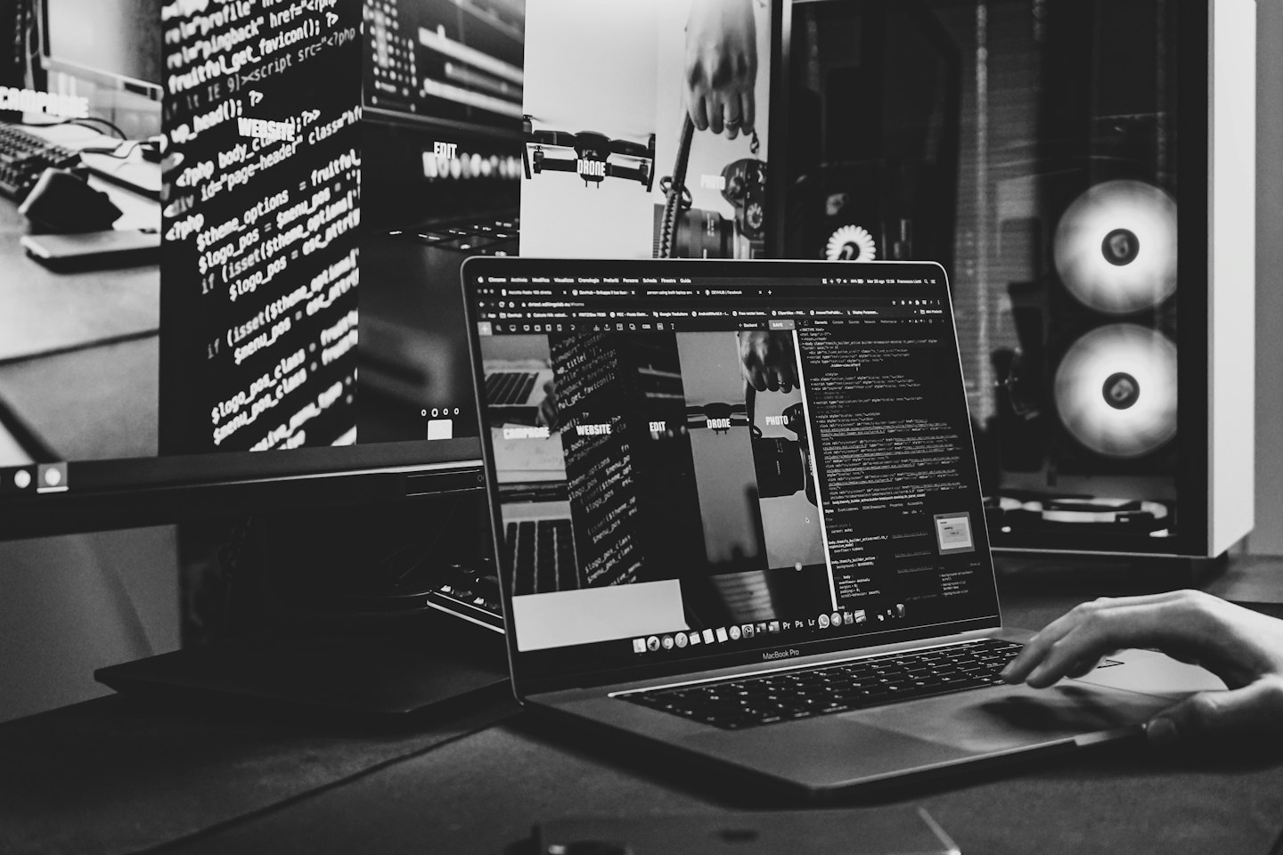 Dłoń używająca gładzika MacBooka Pro z kodem na ekranie.